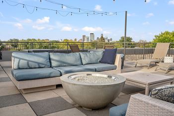 A patio with a blue couch, a bowl, and a table.